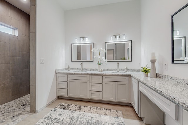 bathroom featuring double vanity, a walk in shower, baseboards, and a sink