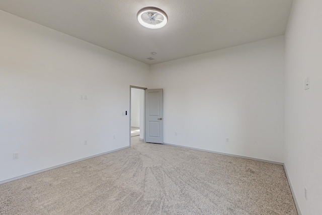 spare room with light carpet and baseboards