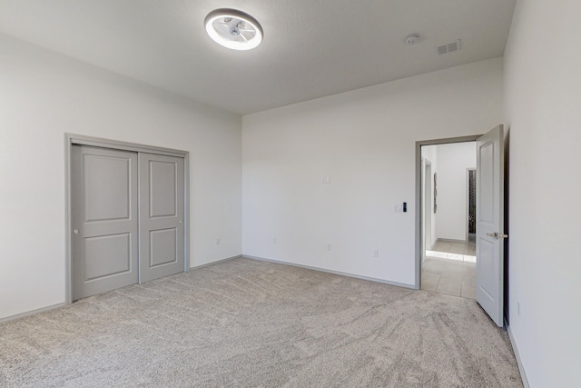 unfurnished bedroom with visible vents, light carpet, baseboards, and a closet