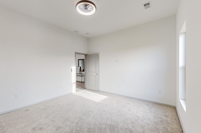 empty room with visible vents, light colored carpet, and baseboards