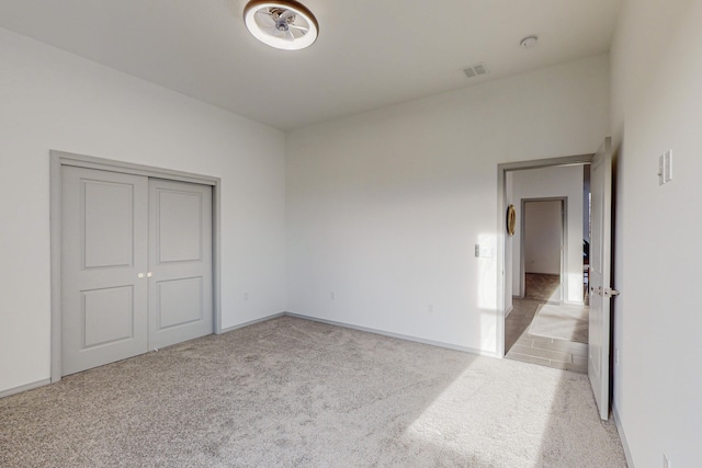 unfurnished bedroom with visible vents, baseboards, light colored carpet, and a closet