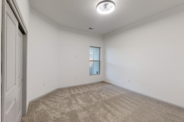 unfurnished bedroom featuring a closet, visible vents, light colored carpet, and baseboards