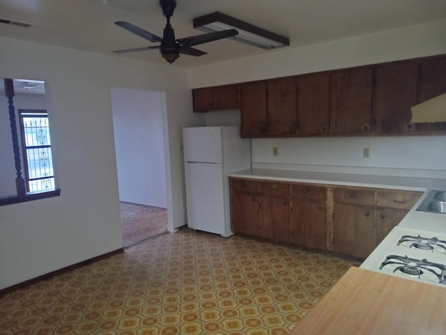 kitchen with white fridge, cooktop, ceiling fan, dark brown cabinetry, and sink