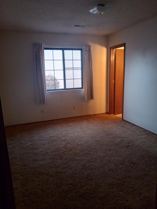 empty room with a textured ceiling and carpet