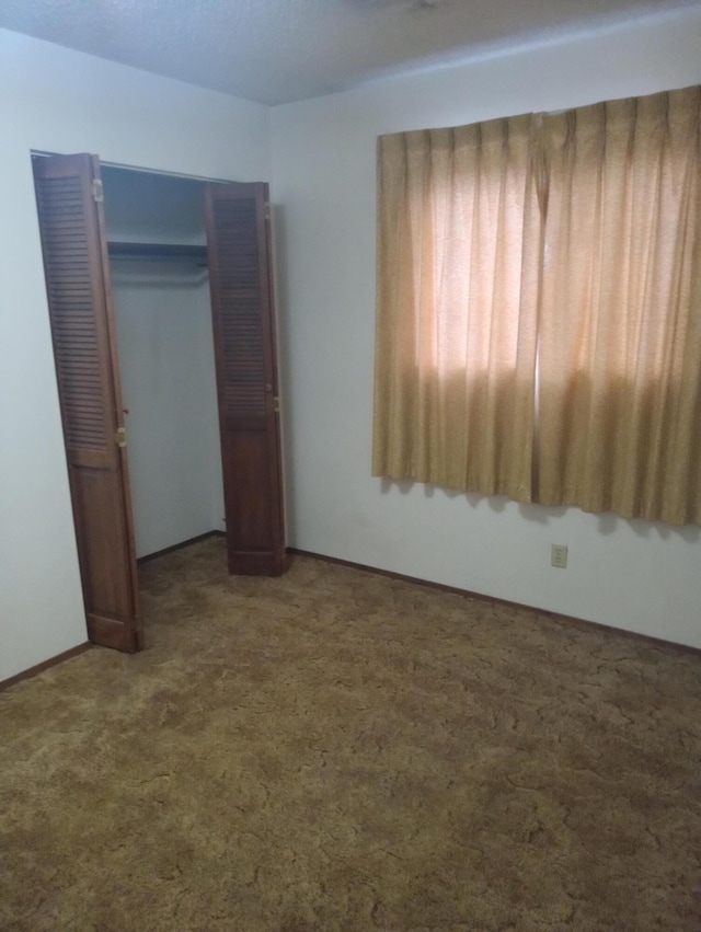 unfurnished bedroom featuring a closet and dark colored carpet