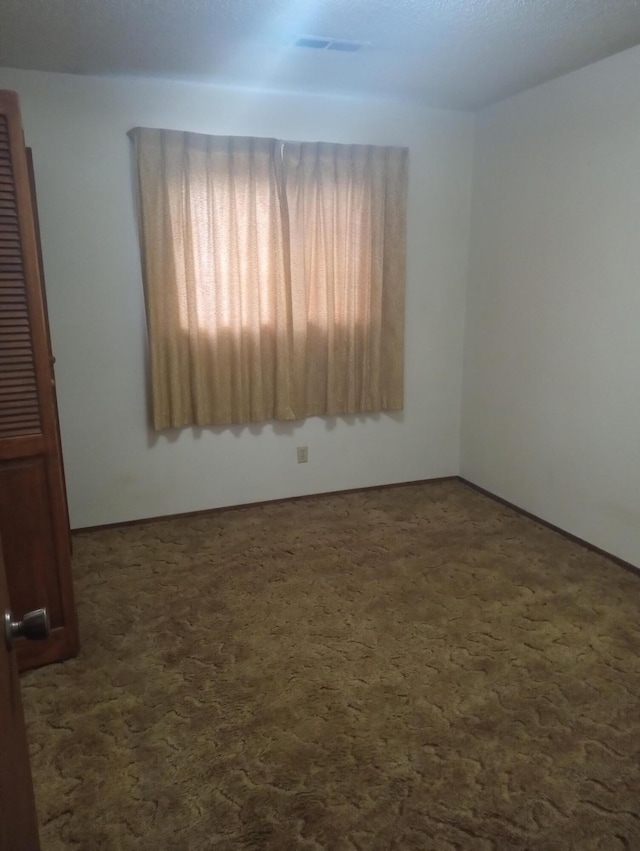 spare room featuring dark colored carpet