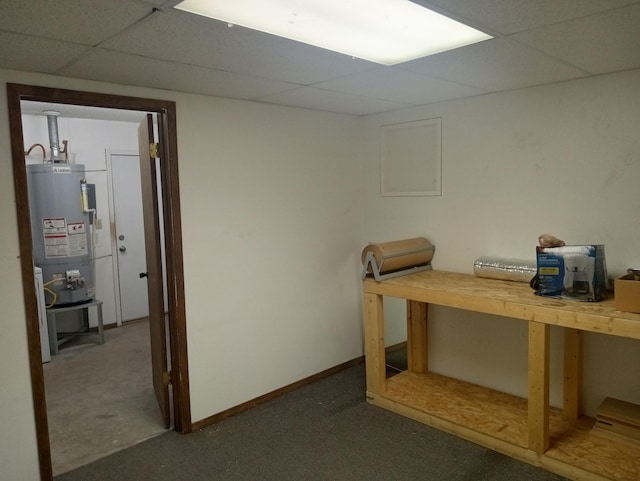 basement featuring a paneled ceiling and water heater