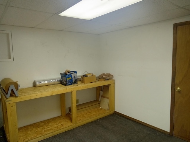 basement featuring a drop ceiling and dark carpet