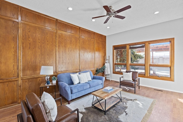 living room featuring a textured ceiling, light hardwood / wood-style floors, and ceiling fan