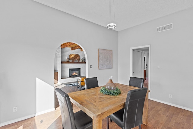 dining room featuring a fireplace, wood-type flooring, and a textured ceiling