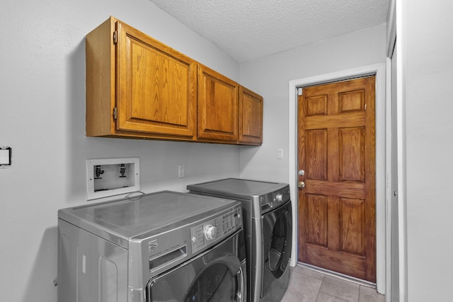 laundry room with light tile patterned floors, cabinets, a textured ceiling, and independent washer and dryer