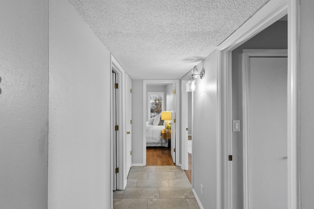 hall featuring light tile patterned floors and a textured ceiling