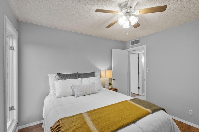 bedroom with a textured ceiling, hardwood / wood-style flooring, and ceiling fan