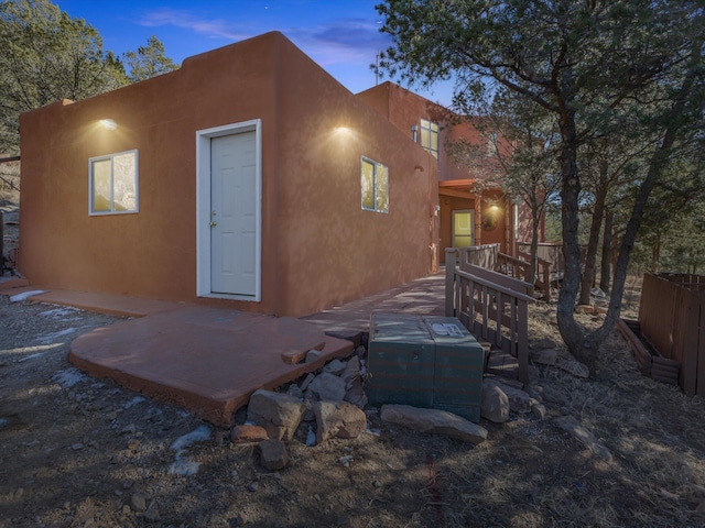 back house at dusk with a patio and a wooden deck