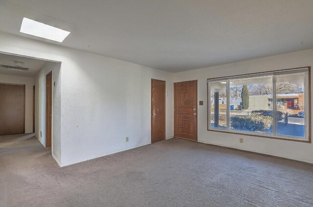 carpeted empty room featuring a skylight