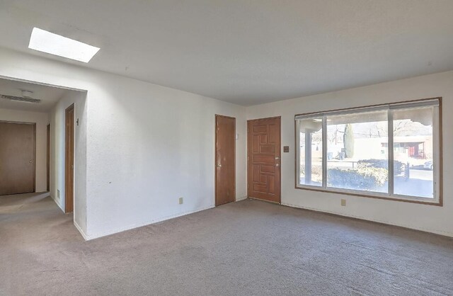 carpeted empty room with a skylight