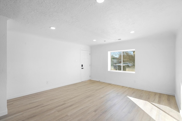 unfurnished room featuring a textured ceiling and light hardwood / wood-style floors