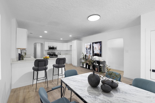 dining area featuring sink, a textured ceiling, and light hardwood / wood-style flooring