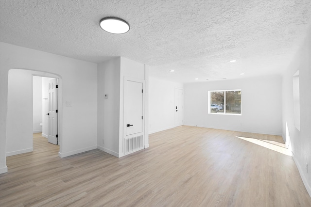 unfurnished room with light wood-type flooring and a textured ceiling