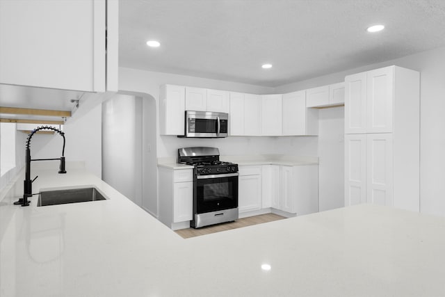 kitchen featuring white cabinets, light wood-type flooring, appliances with stainless steel finishes, and sink