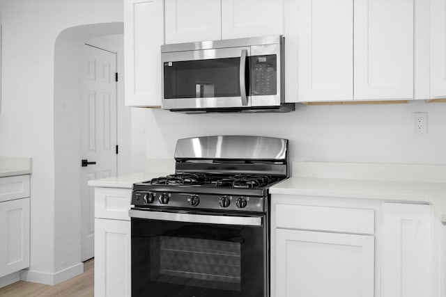 kitchen featuring white cabinets, black gas range, and light hardwood / wood-style flooring