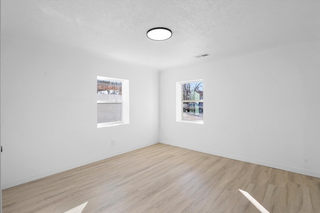 spare room featuring a textured ceiling and light hardwood / wood-style flooring