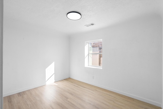 unfurnished room with light wood-type flooring and a textured ceiling