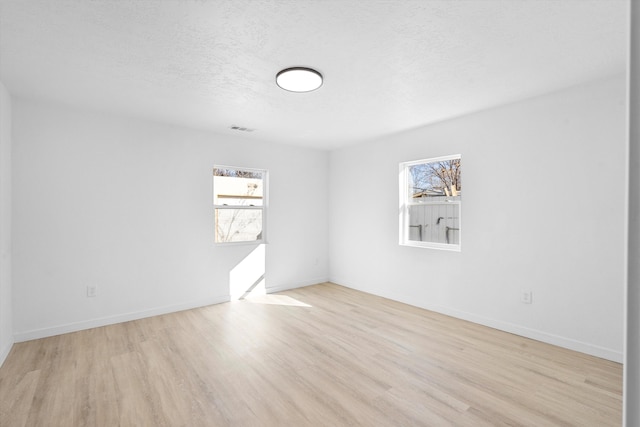 empty room featuring light wood-type flooring and a textured ceiling