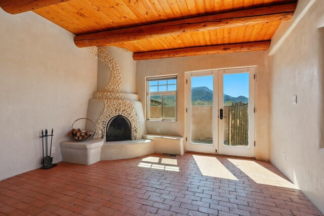 living room with wood ceiling, beamed ceiling, and a stone fireplace