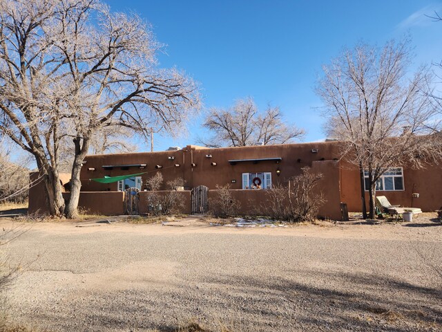 pueblo revival-style home with a fenced front yard and a gate