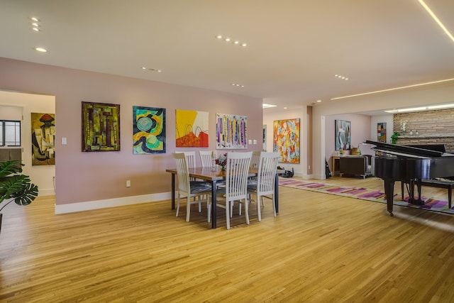 dining space featuring light wood-type flooring and a fireplace