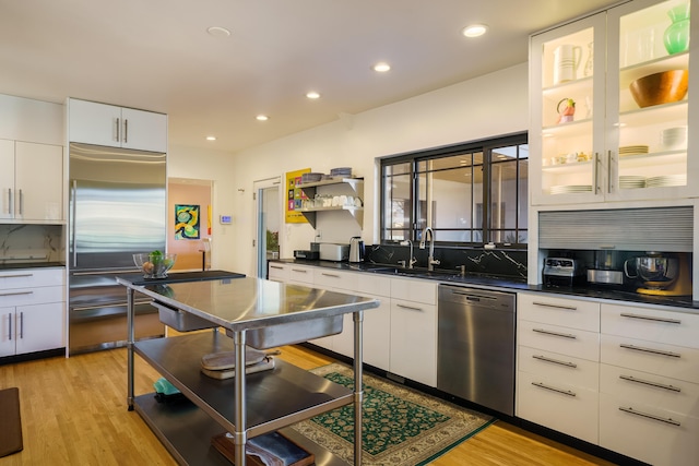 kitchen featuring stainless steel appliances, white cabinets, sink, and light hardwood / wood-style flooring