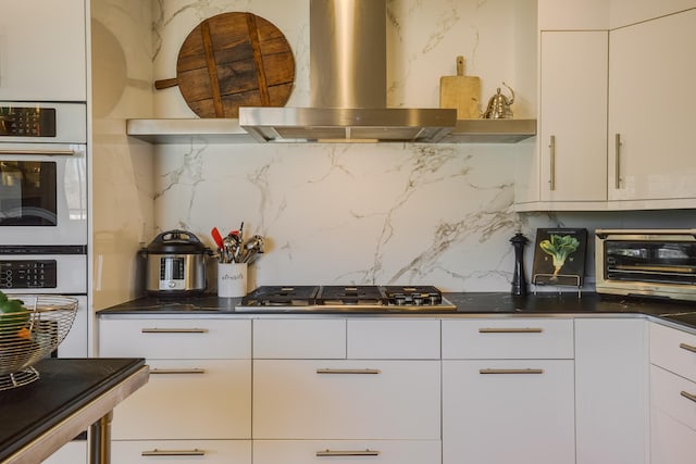 kitchen with double oven, white cabinets, ventilation hood, and decorative backsplash