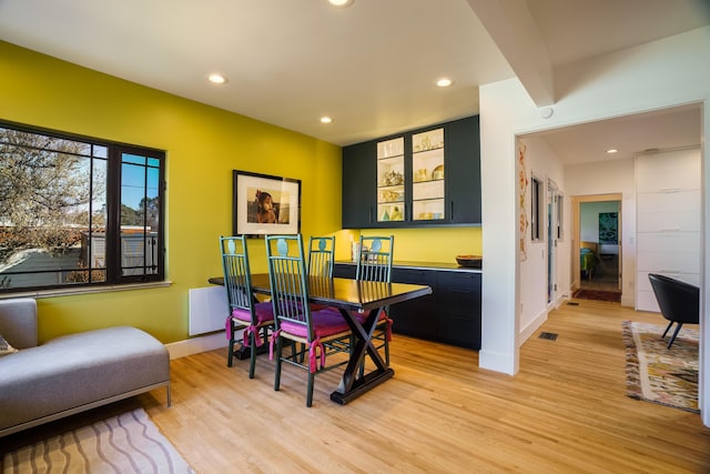 dining room with light hardwood / wood-style floors and beamed ceiling