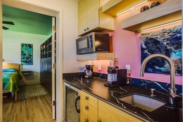 kitchen featuring light hardwood / wood-style flooring, light brown cabinetry, wine cooler, dark stone countertops, and sink