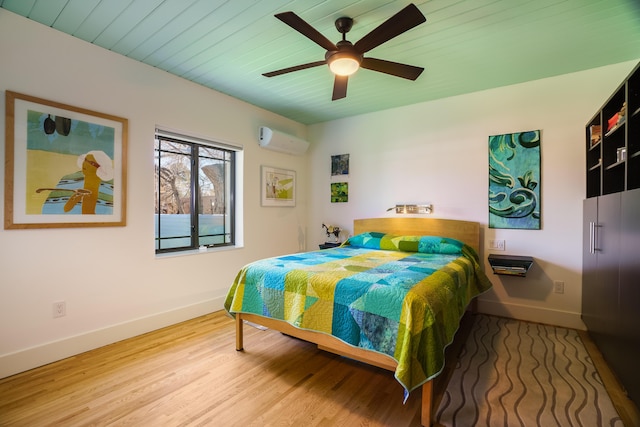 bedroom with ceiling fan, hardwood / wood-style flooring, and a wall mounted AC