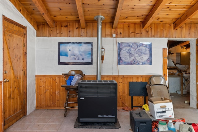 interior details with beamed ceiling, wood ceiling, wooden walls, and a wood stove