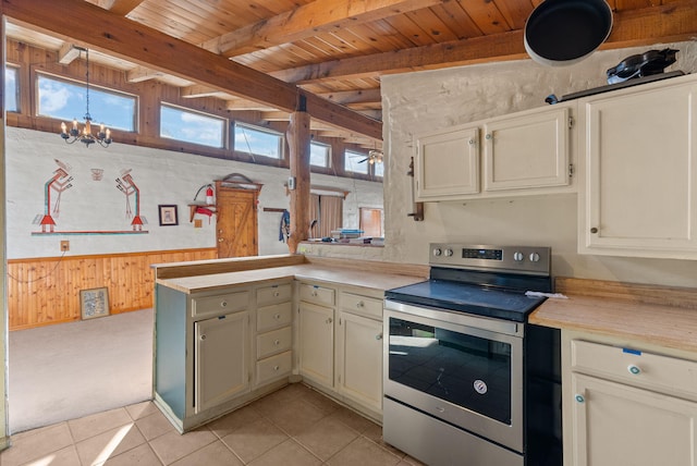 kitchen with a chandelier, light tile patterned floors, wooden walls, kitchen peninsula, and stainless steel electric stove