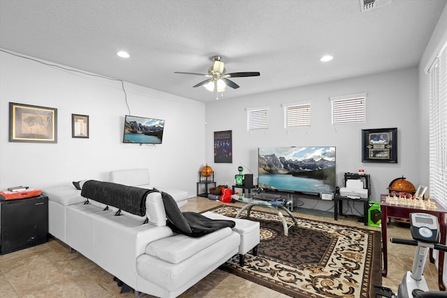 living room featuring ceiling fan, light tile patterned floors, and a textured ceiling