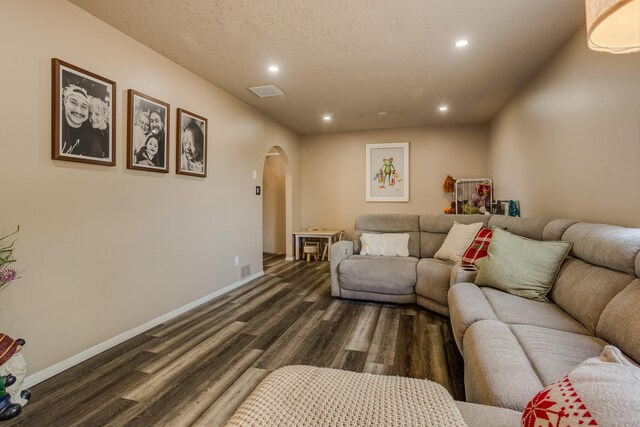 living room with a textured ceiling and dark hardwood / wood-style floors