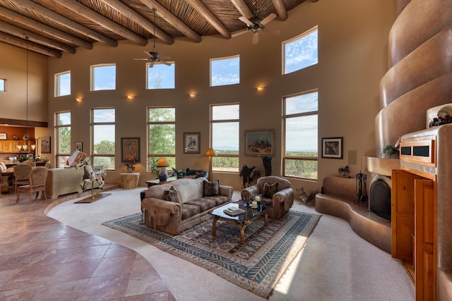 living room featuring beamed ceiling, a towering ceiling, ceiling fan, and wooden ceiling