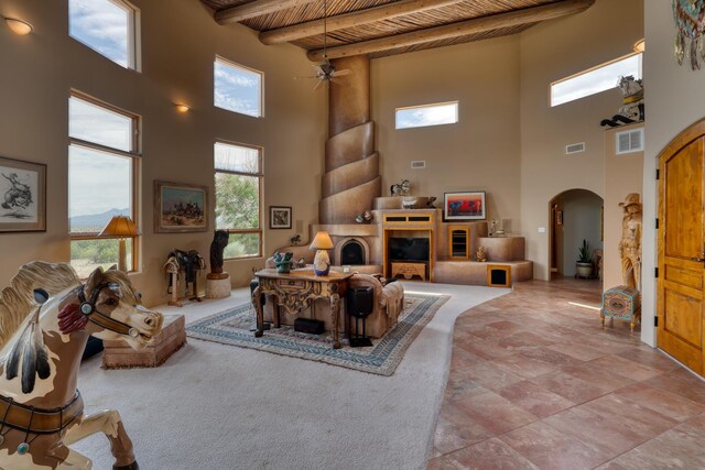 living room featuring beamed ceiling, a towering ceiling, ceiling fan, and wooden ceiling