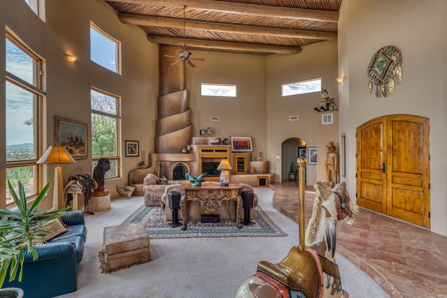 carpeted living room with a towering ceiling, beamed ceiling, and wooden ceiling