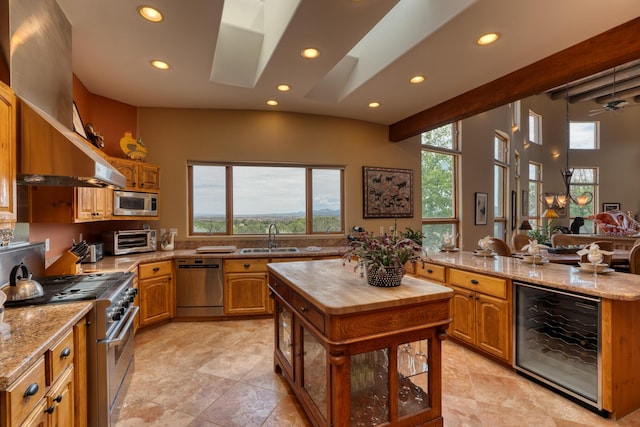 kitchen with light stone countertops, beverage cooler, appliances with stainless steel finishes, and sink