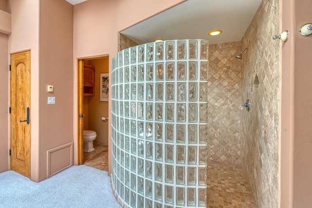 bathroom with tiled shower and toilet