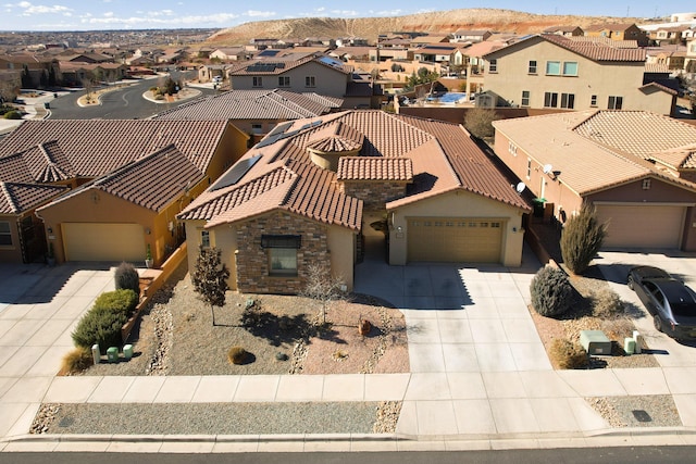 exterior space featuring driveway, a garage, a tile roof, a residential view, and stucco siding