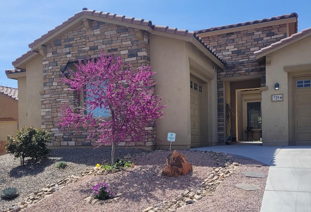 exterior space with stone siding, a garage, a tiled roof, and stucco siding