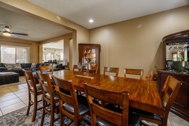 tiled dining area with a textured ceiling and ceiling fan