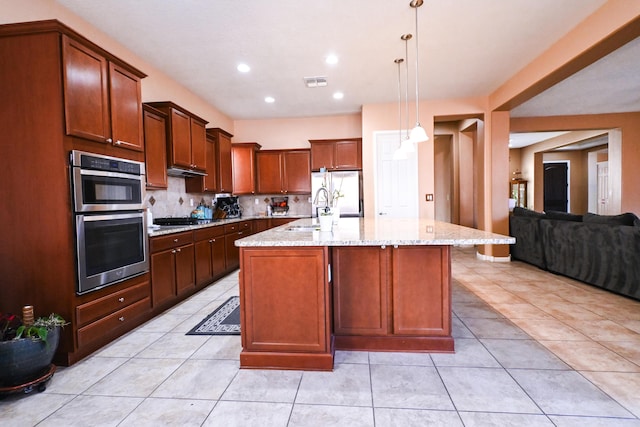 kitchen featuring a sink, visible vents, appliances with stainless steel finishes, backsplash, and light stone countertops