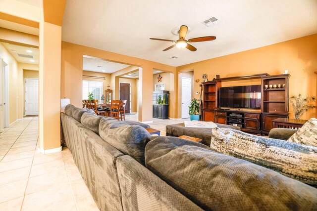 living room with ceiling fan, visible vents, baseboards, and light tile patterned flooring